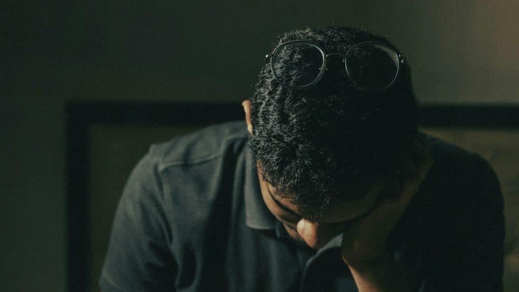 A person with glasses pushed up on their head, looks down in distress.