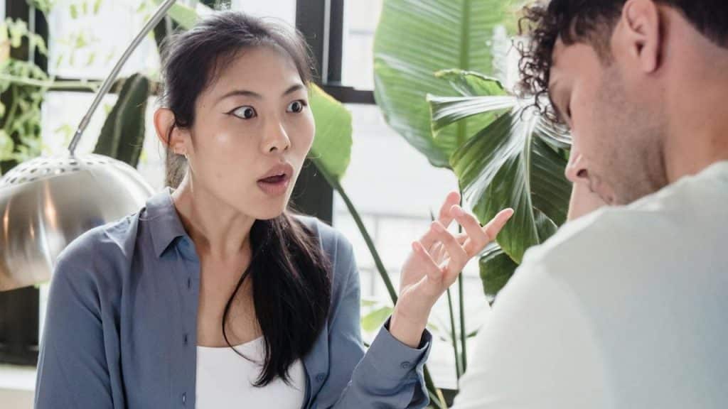 A surprised woman gestures while talking to a man.
