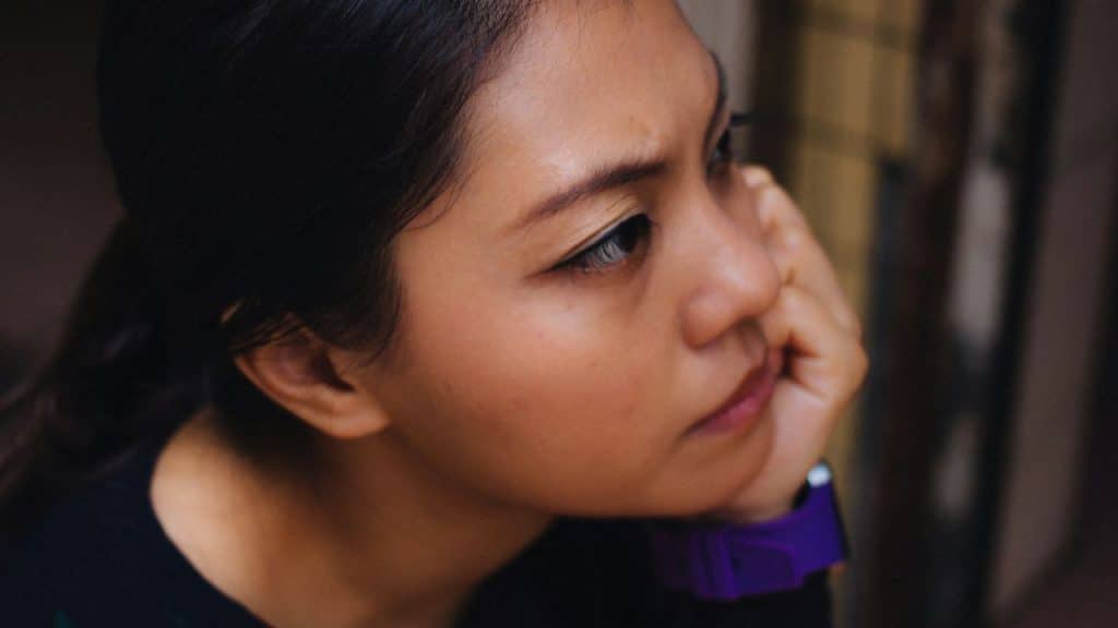 A young woman looks to the side with a serious, pensive expression.