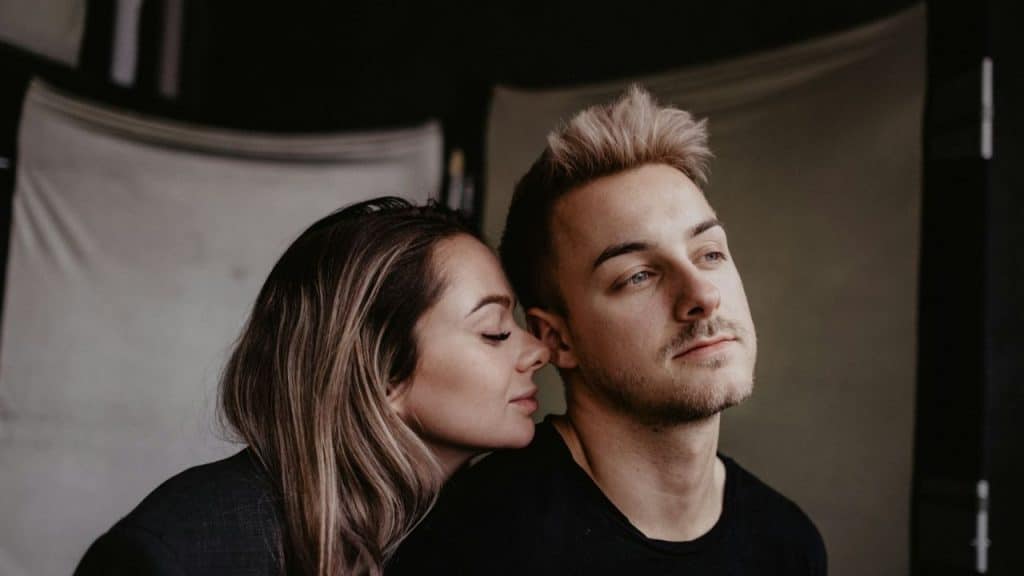 A woman rests her head on a man's shoulder.
