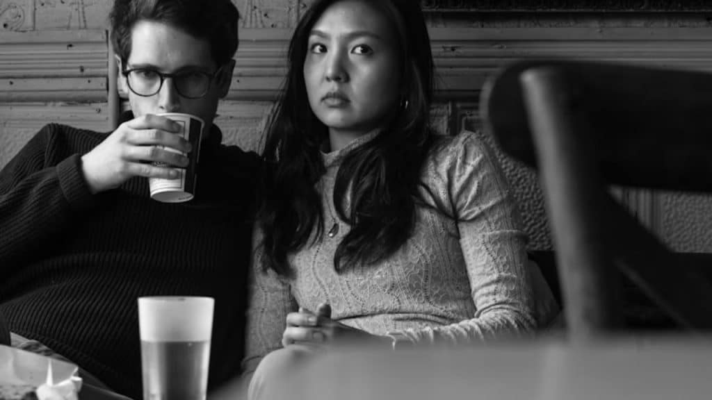 Couple at a café, man nodding excessively while woman looks skeptical