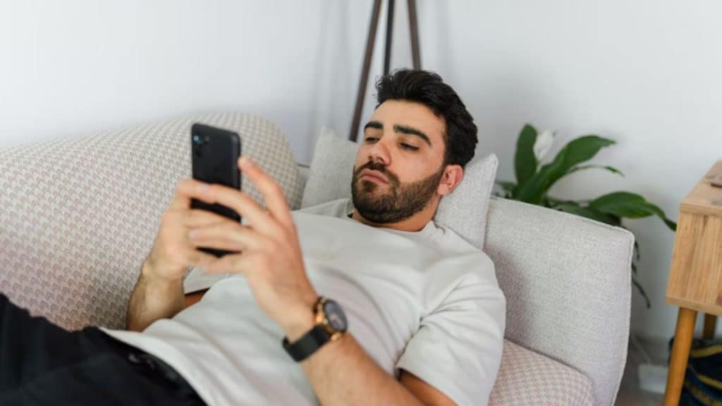 Man slouched on couch while texting compliments to partner