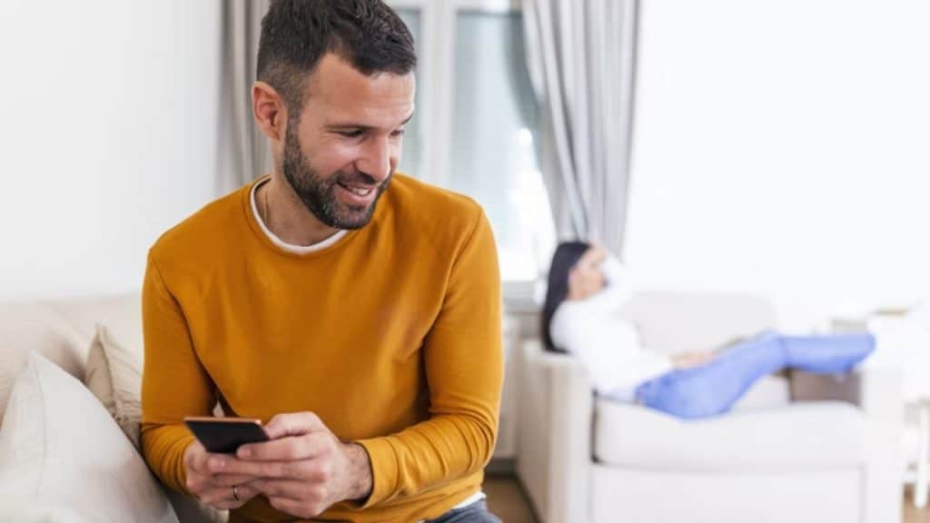 Man glued to his phone while woman puts hers aside, looking annoyed