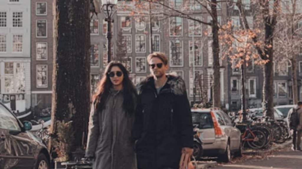 Man following girlfriend everywhere, while she looks slightly annoyed