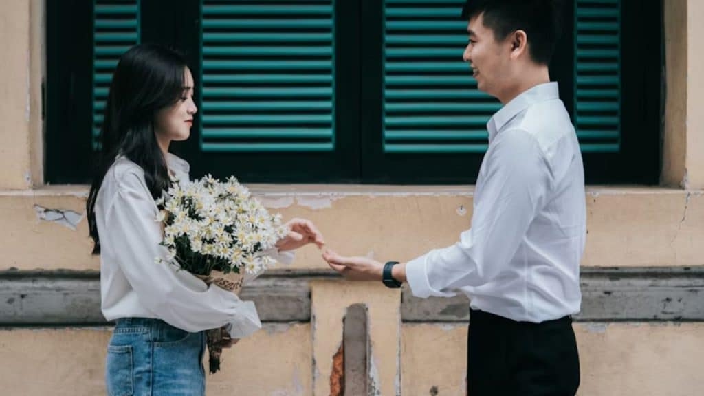 Man giving flowers with expectant look while woman looks uncomfortable