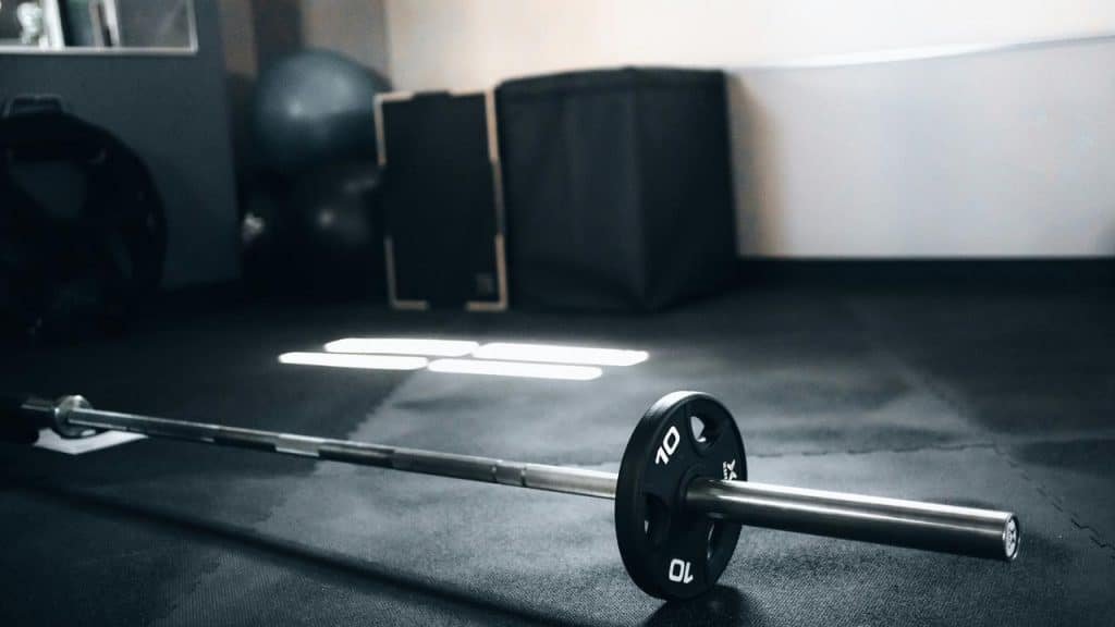 A barbell with plates resting on a gym floor.