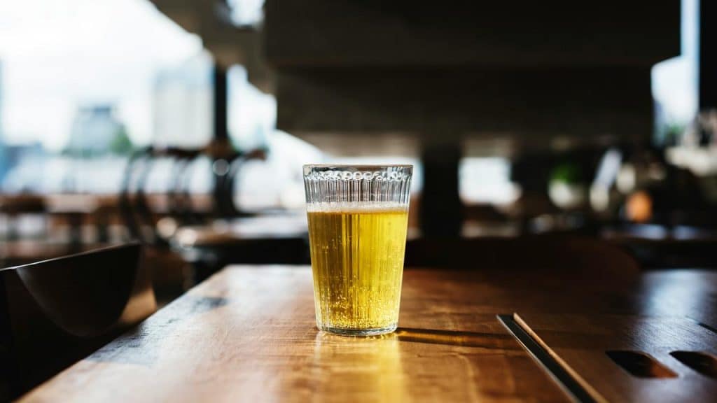 A glass of beer on a wooden table.