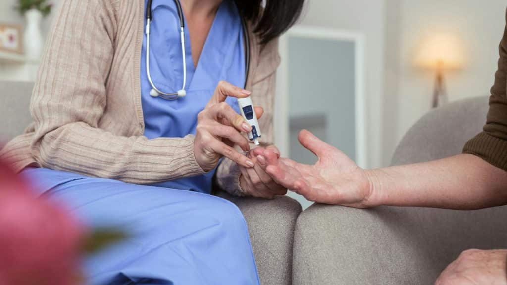 A nurse checks a patient's blood sugar level.