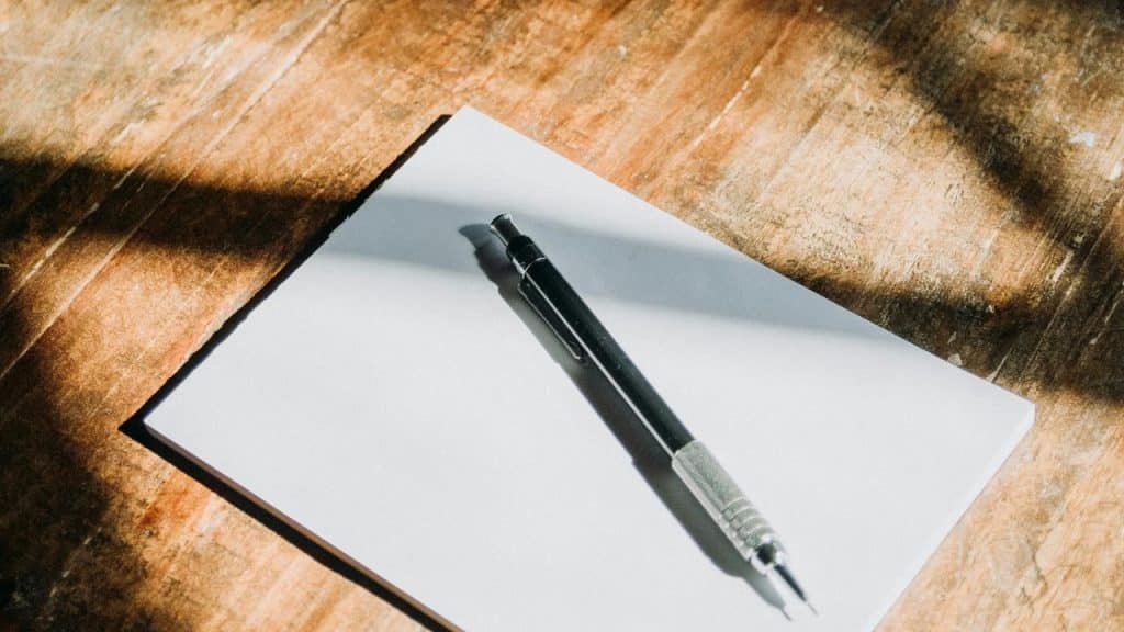 A pen resting on a blank sheet of paper.