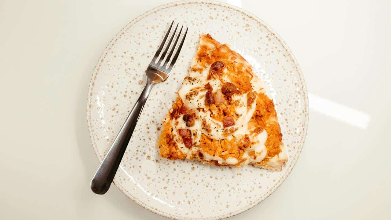 A slice of pizza on a plate with a fork.