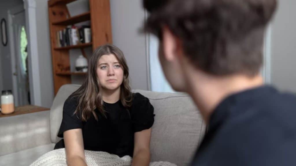 Woman looking down sadly while partner scolds her
