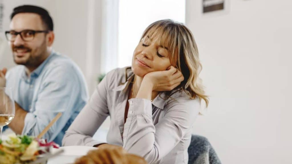 Couple sitting silently as the man talks his wife closes her eyes 