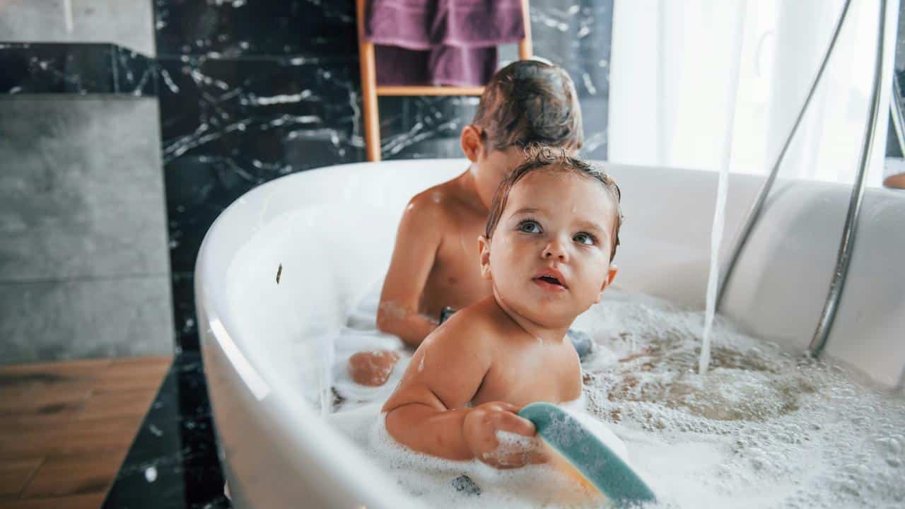 A baby and toddler in a bubble bath.