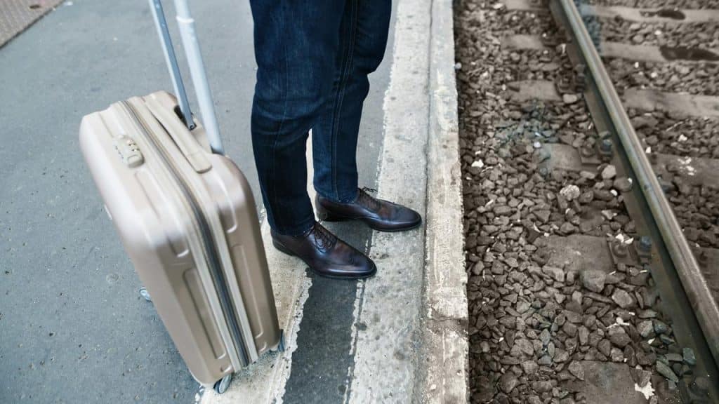 A traveler with a suitcase at a train station.