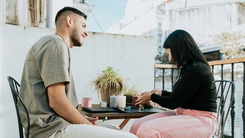 A smiling man and a woman play a board game on a balcony.