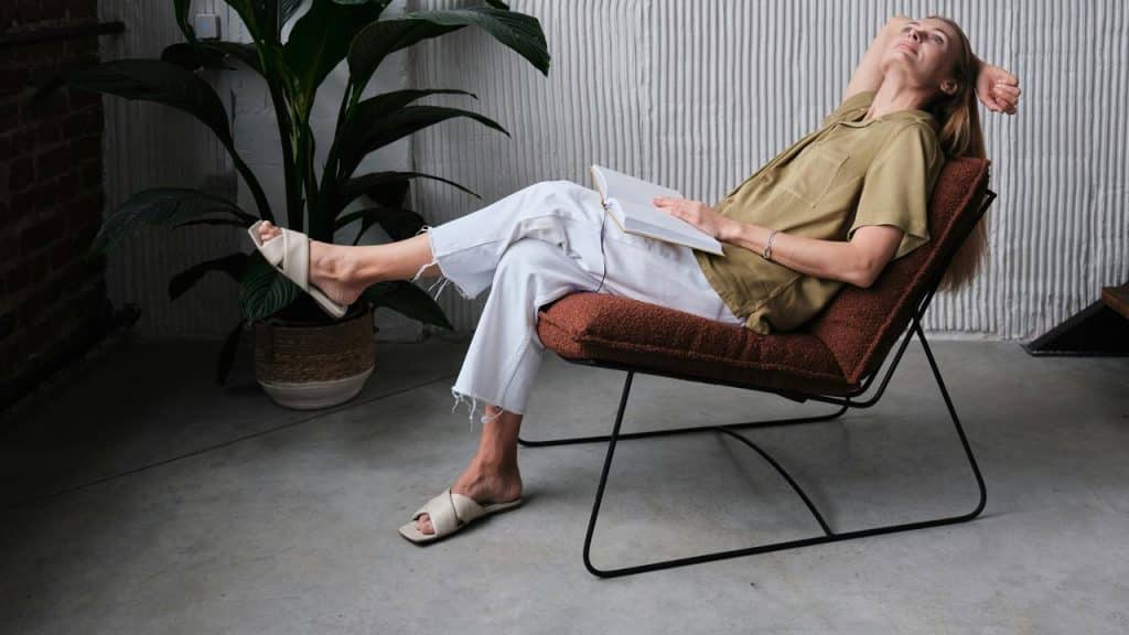 A woman relaxing on a chair with a notebook in her hand.