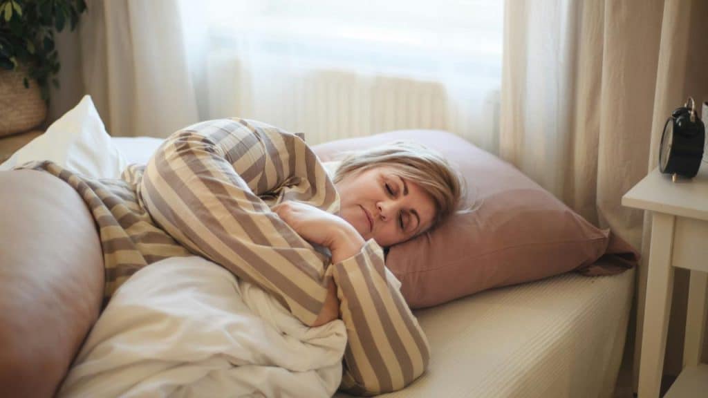 A person sleeping in bed with striped pajamas.