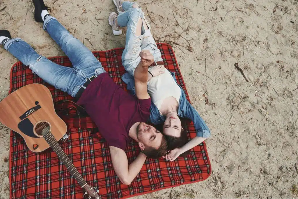 A man and woman laying together at the sand