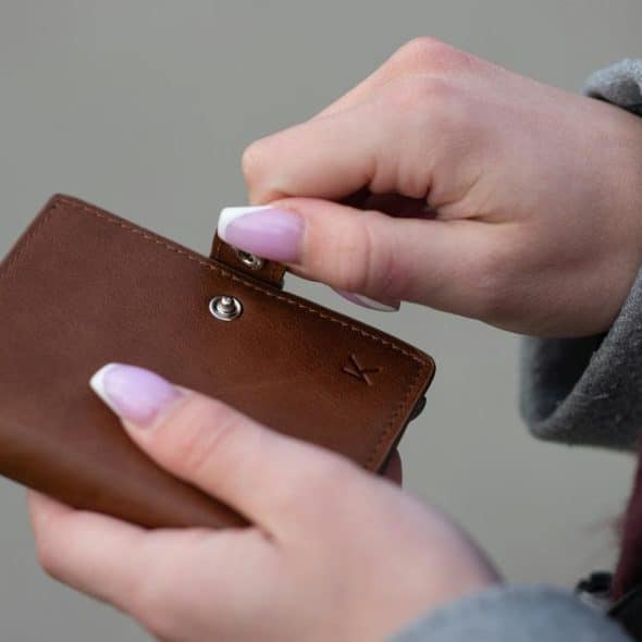 A person opening a brown leather wallet.