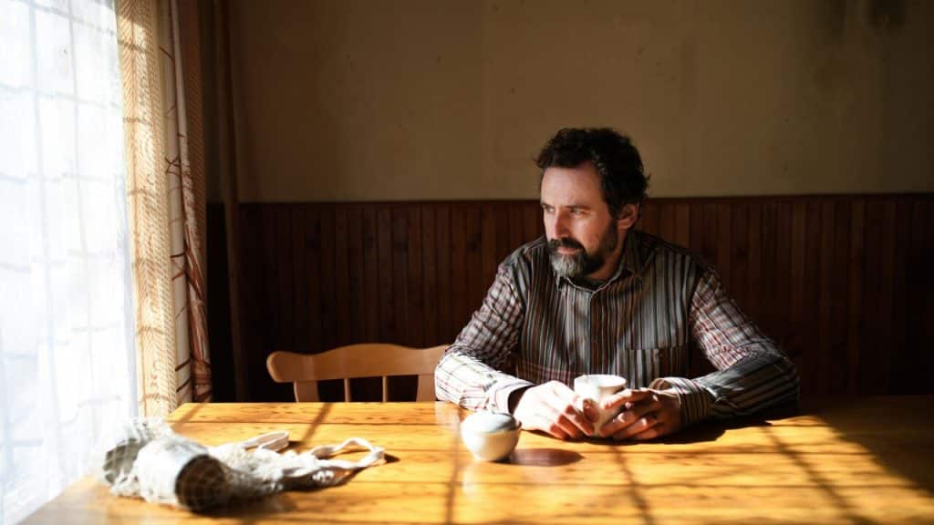 A man looking sad while gazing out the window