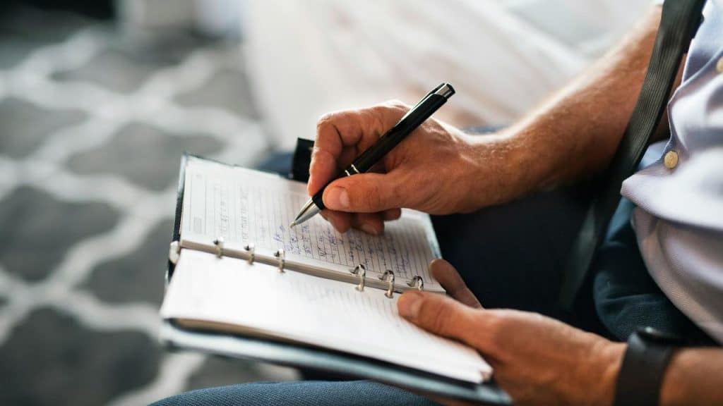 A man writing notes in a planner.