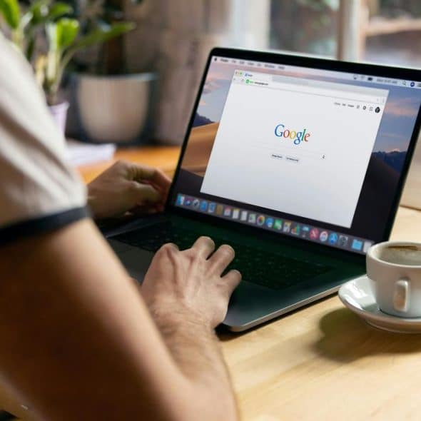 A person using a laptop with a Google window open.