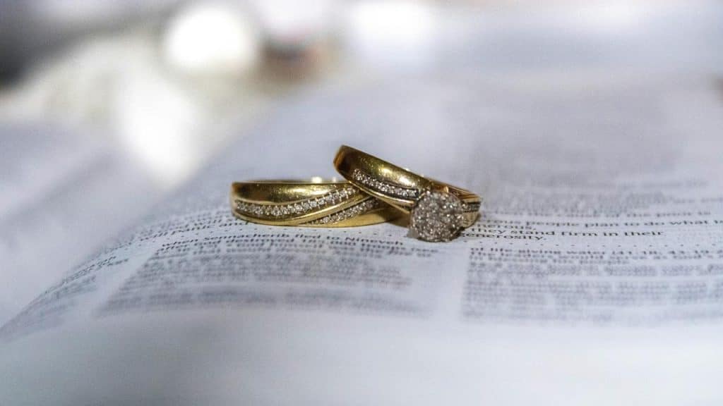 A pair of gold wedding rings resting on an open book.