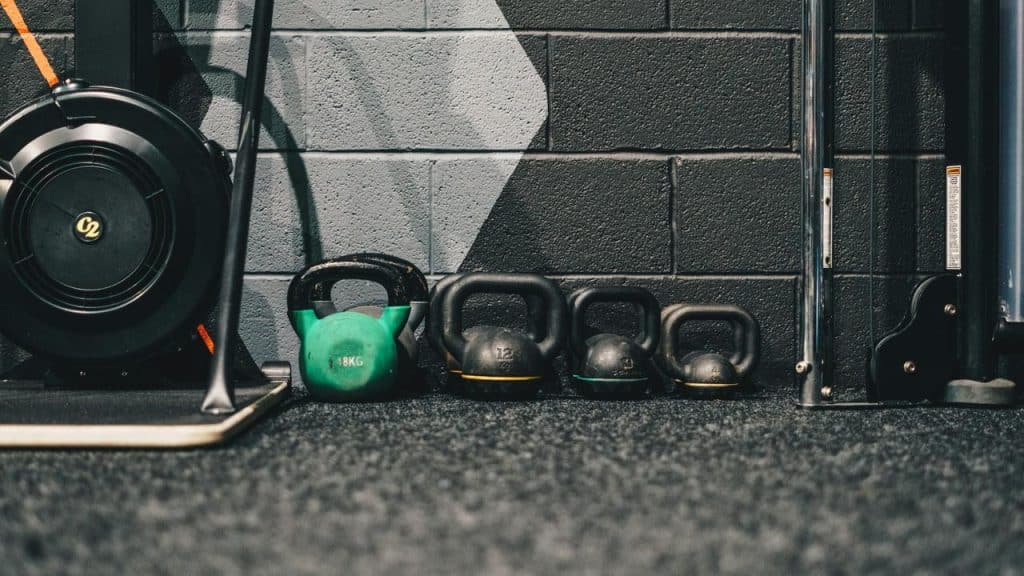 A row of kettlebells lined up against a gym wall.