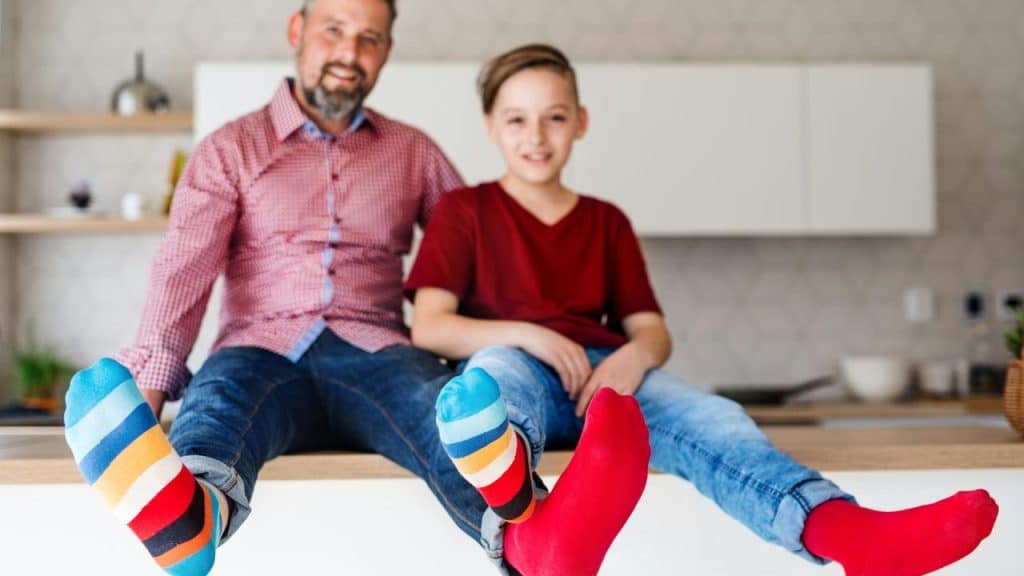 A man and a kid showing off colorful socks.
