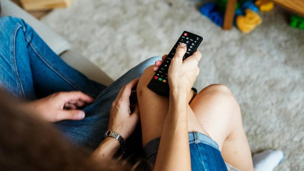 A couple holding a TV remote on a couch.