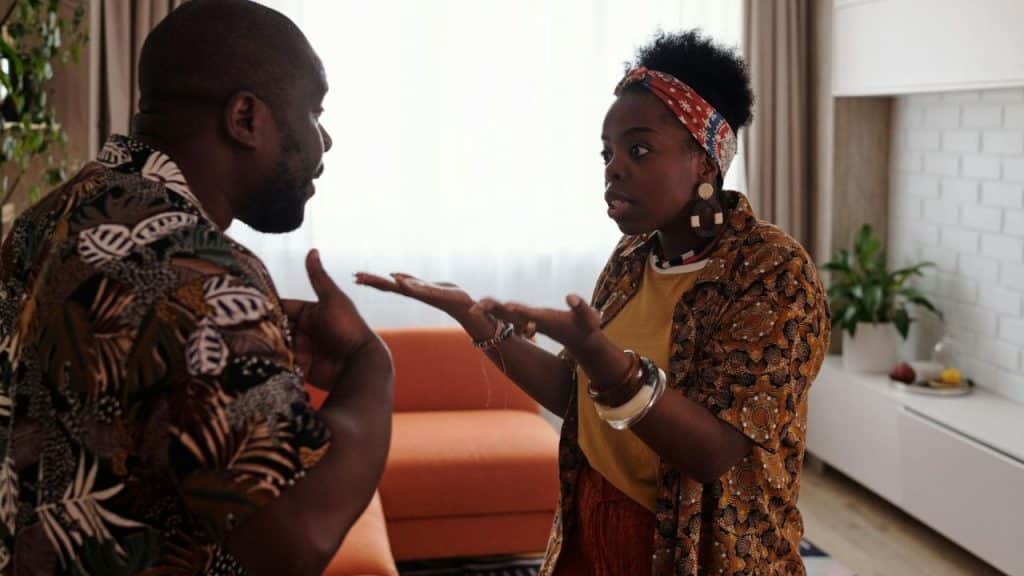 A woman with a patterned headband argues passionately with a man in a patterned shirt.