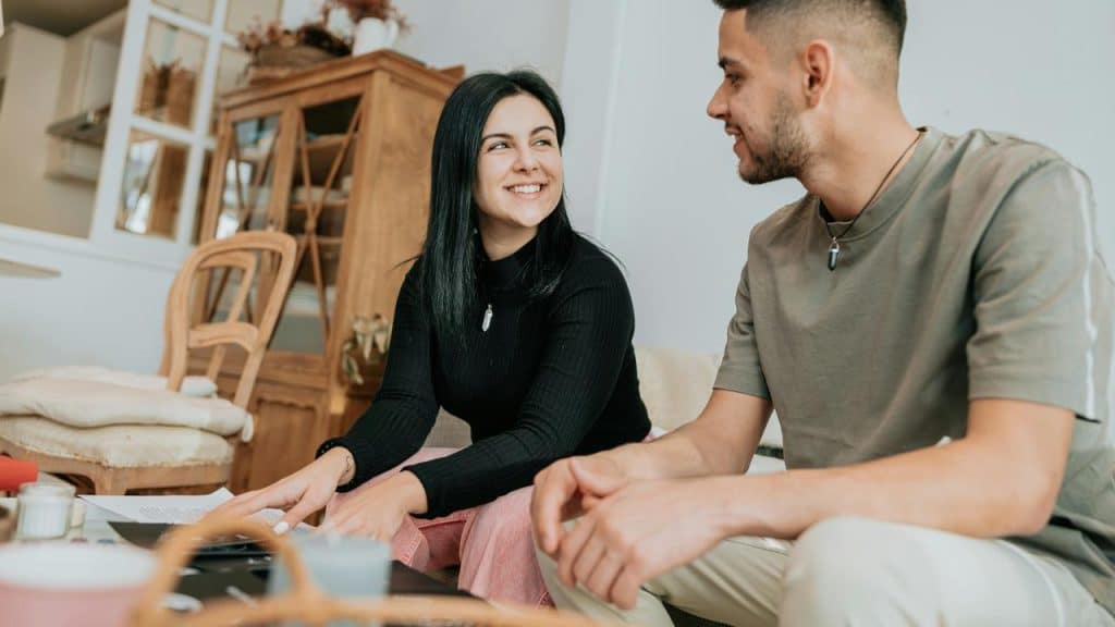 A man and woman smiling while talking at a table.