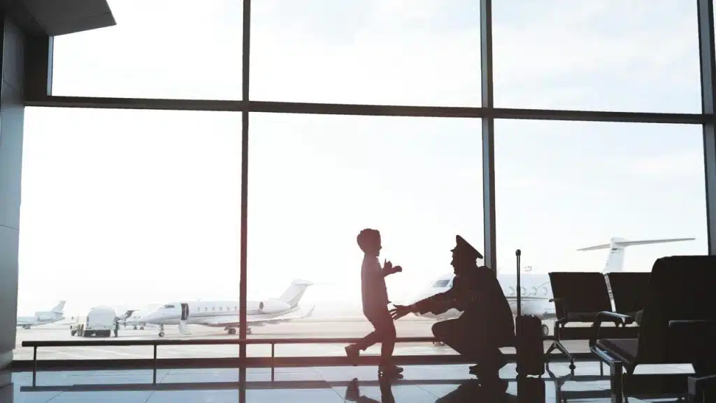 A pilot greeting a child inside an airport terminal.