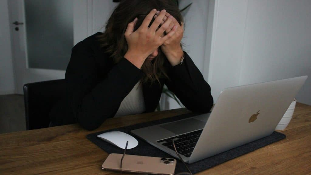 A woman looking stressed in front of a laptop.