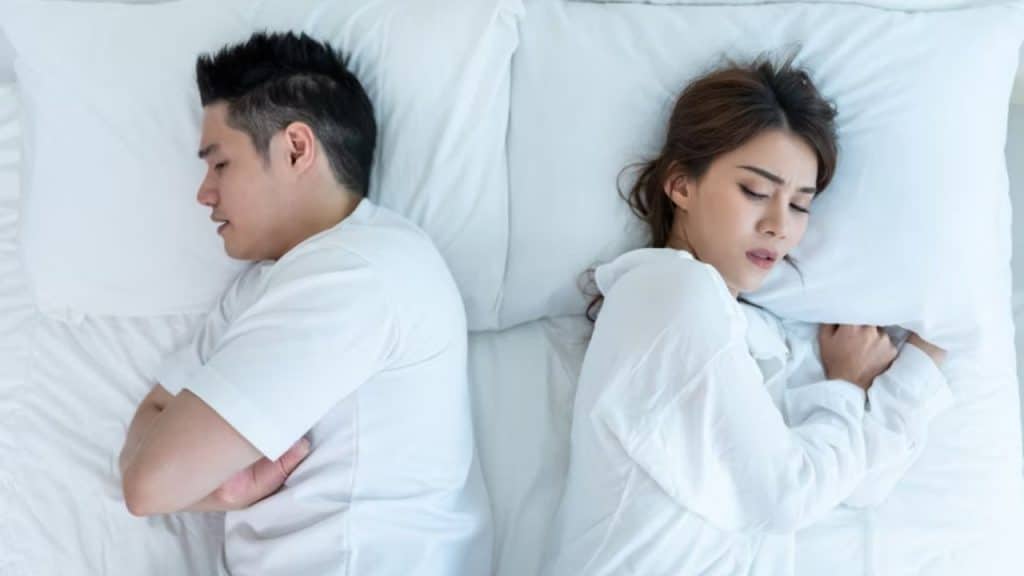 Couple lying in bed facing opposite directions