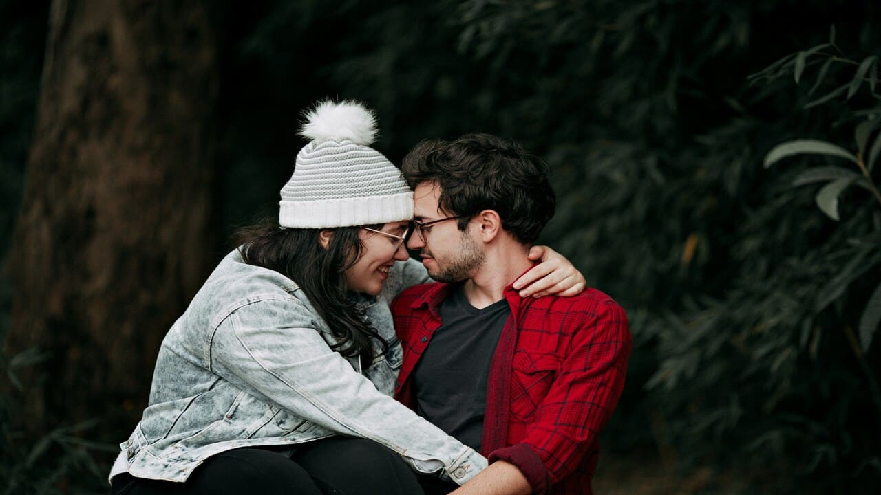 A couple forehead-to-forehead while outdoors.