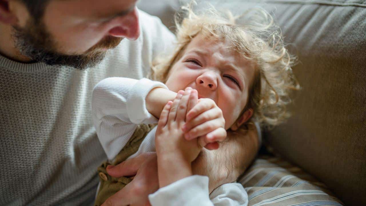 A father comforting his crying toddler.