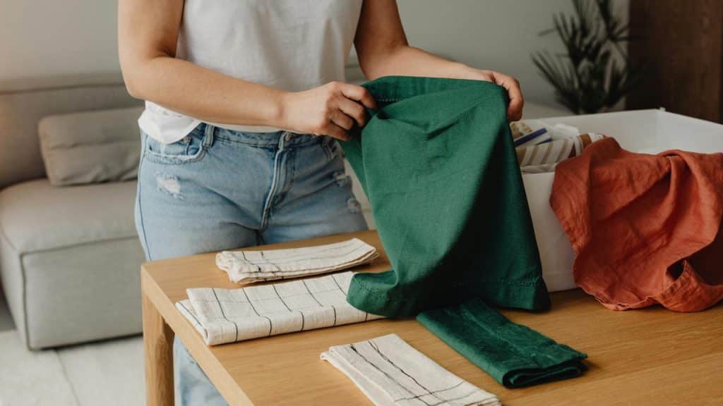 A person folding linens on a wooden table.