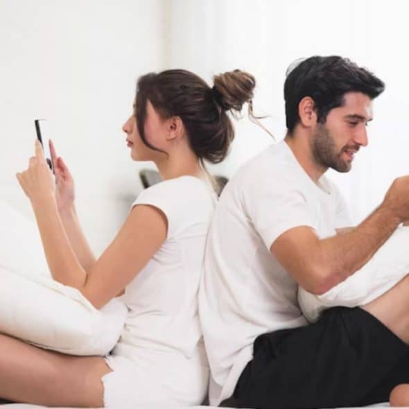 Emotionally distant couple sitting together but disengaged