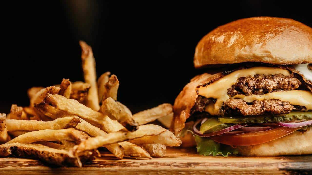 A cheeseburger with fries on a wooden surface.