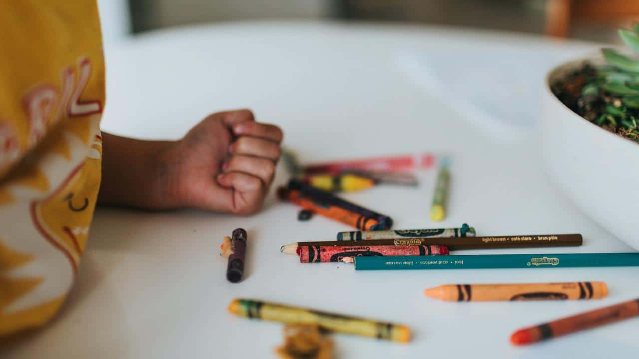 A child with crayons on a table.