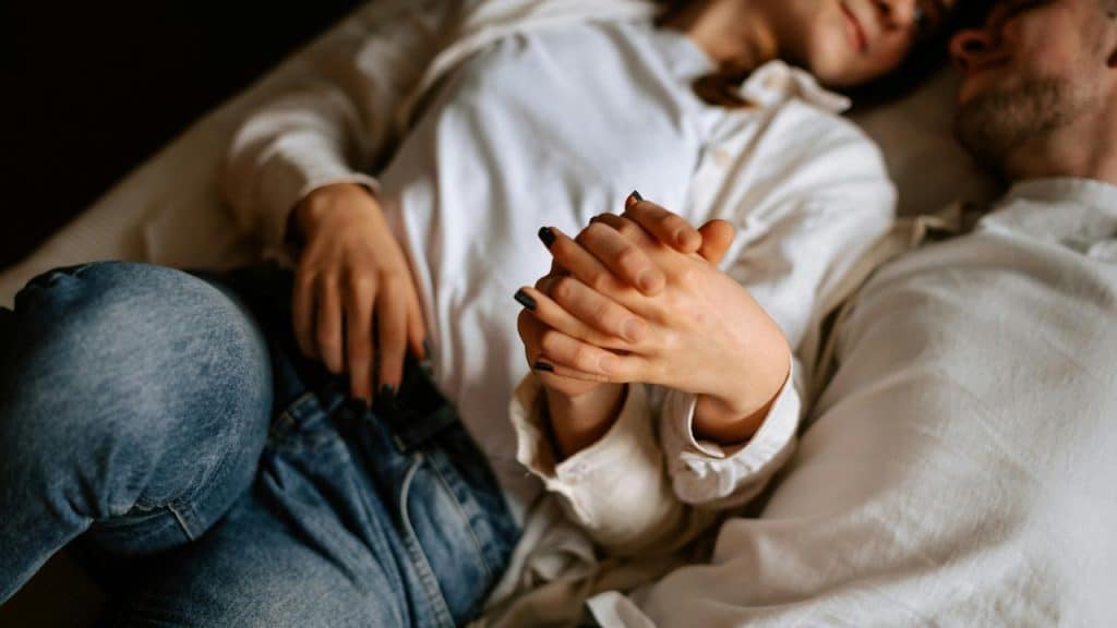 A couple lying down holding hands.