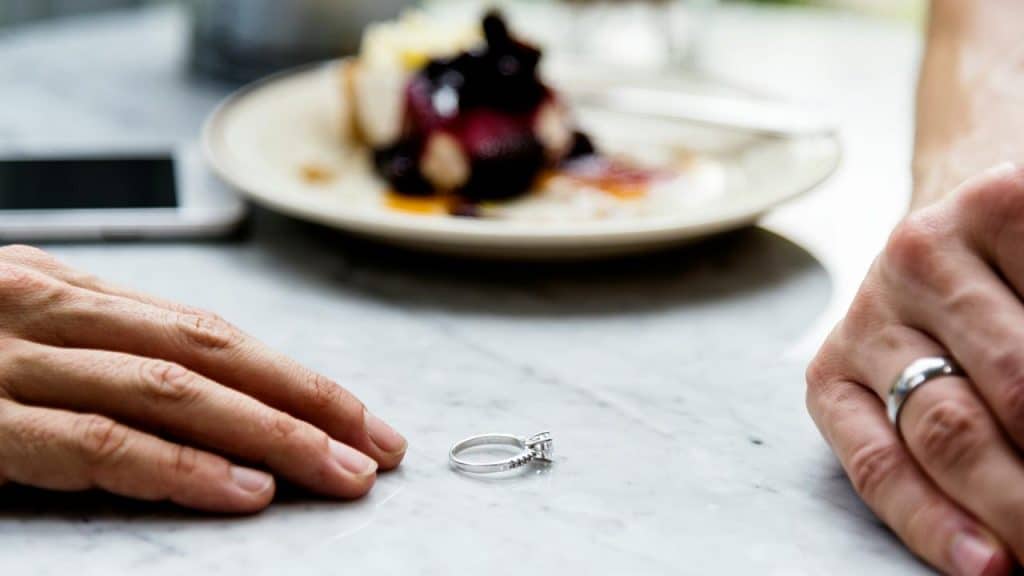 A ring on a table between two hands.