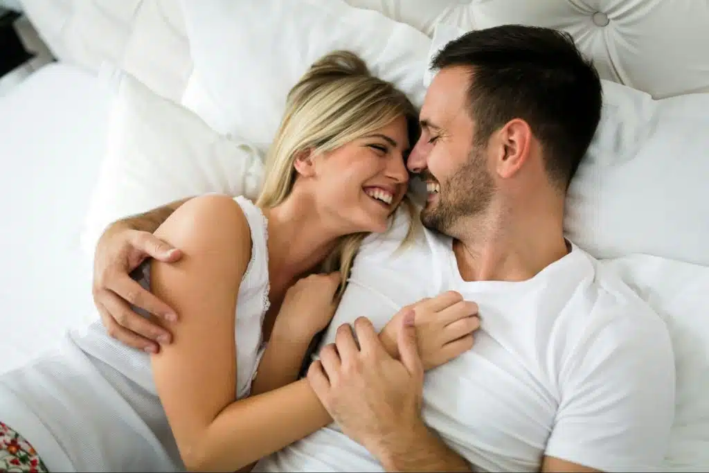 A man and woman cuddling at the bed