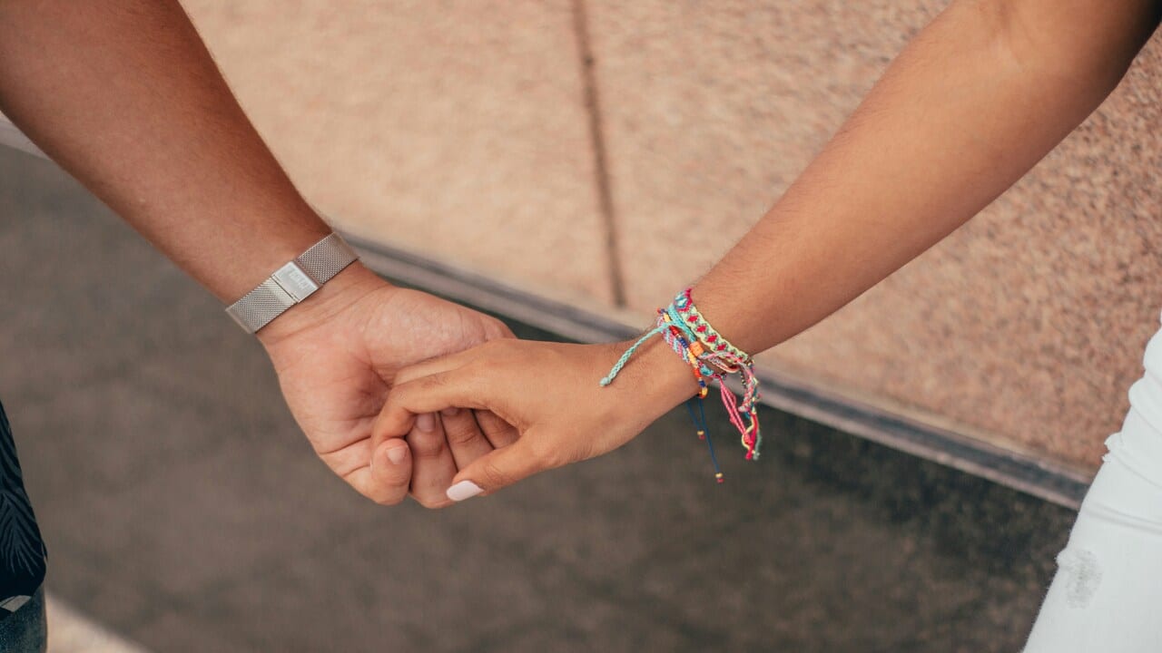 A couple holding hands outdoors.