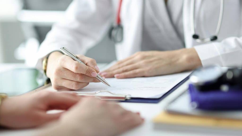 A doctor filling out a medical form during a patient consultation.