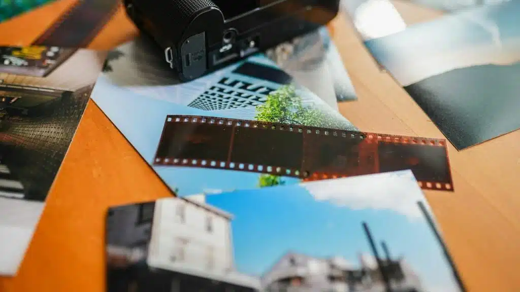 A strip of photo negatives and prints beside a film camera.