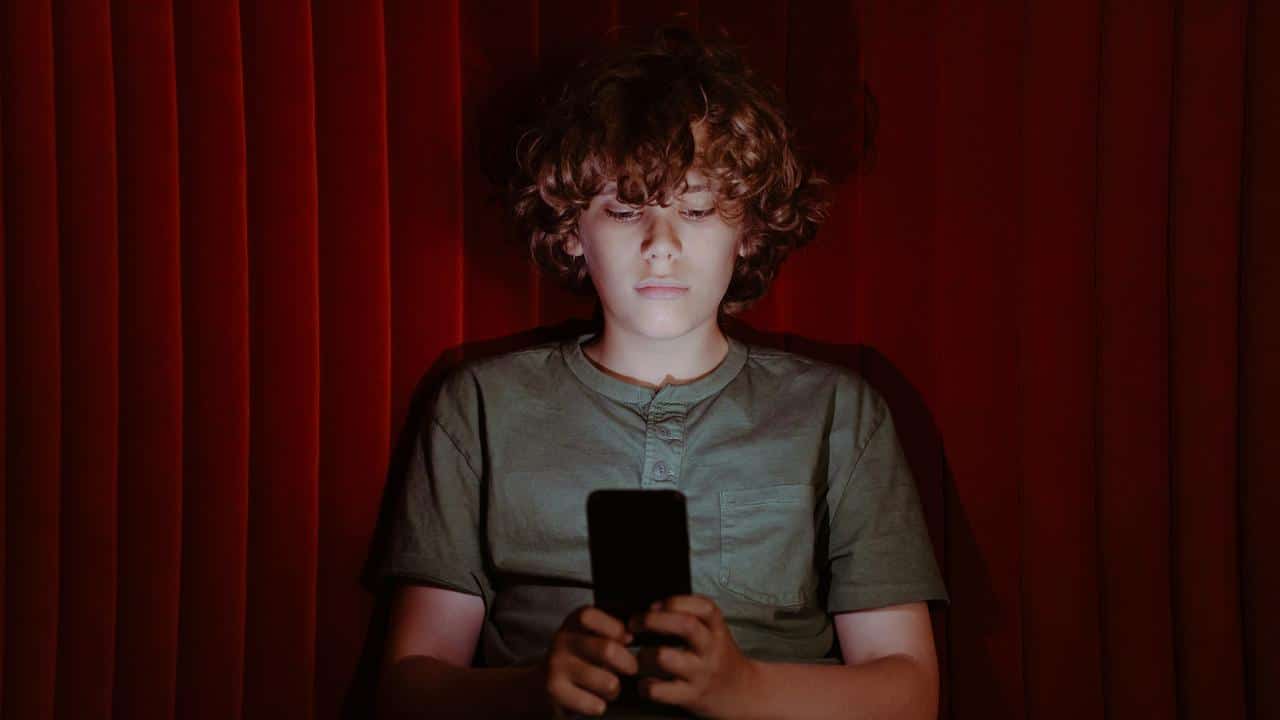 A boy using a smartphone in the dark.