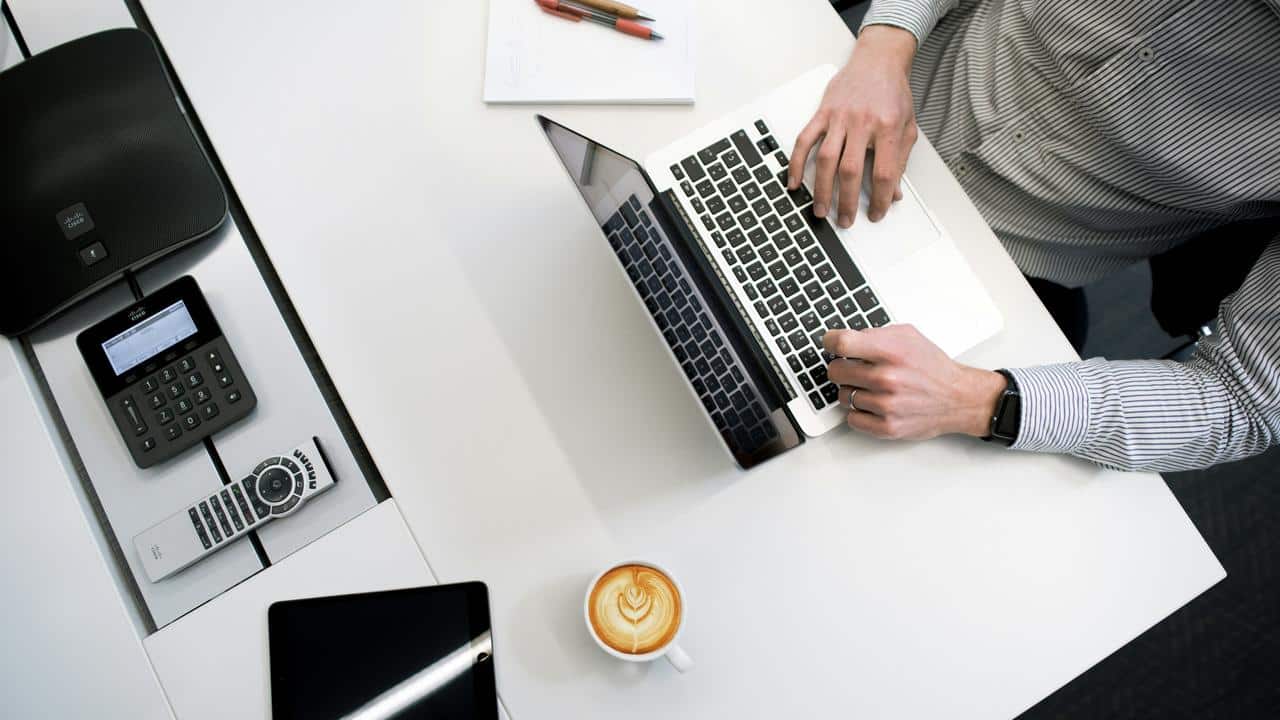 A man typing on a laptop at a modern desk.