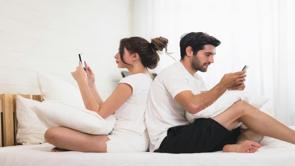 A couple ignoring each other while using their phones.